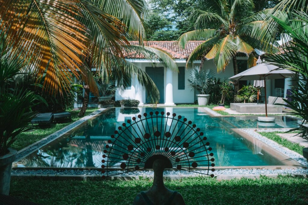 A tranquil tropical villa with a swimming pool surrounded by lush palm trees.
